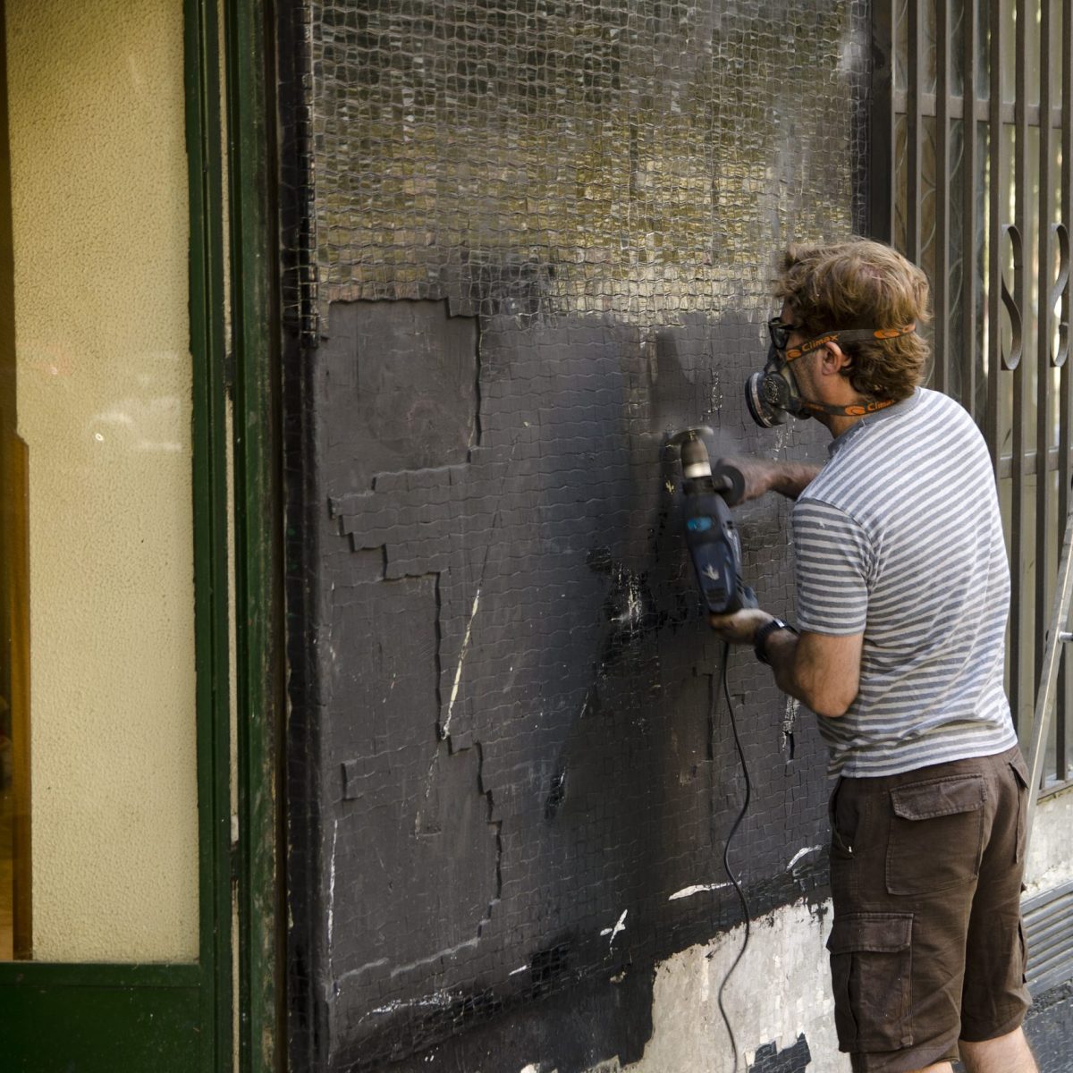 man-smoother-wall-surface-with-wall-grinder-wearing-protection-mask